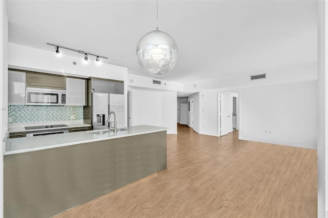 kitchen with pendant lighting, hardwood / wood-style floors, sink, tasteful backsplash, and stainless steel appliances