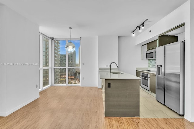 kitchen with pendant lighting, backsplash, sink, an island with sink, and appliances with stainless steel finishes