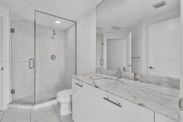 bathroom with tile patterned flooring, vanity, toilet, and a shower with shower door