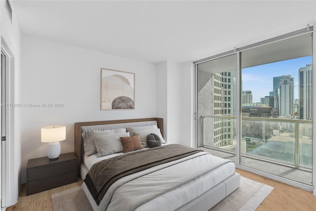 bedroom featuring access to outside, expansive windows, and light wood-type flooring