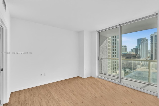 empty room with a wall of windows and hardwood / wood-style flooring