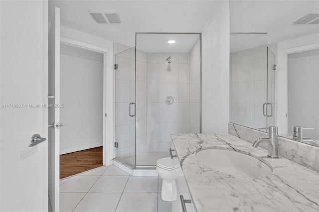 bathroom with tile patterned flooring, vanity, toilet, and a shower with shower door