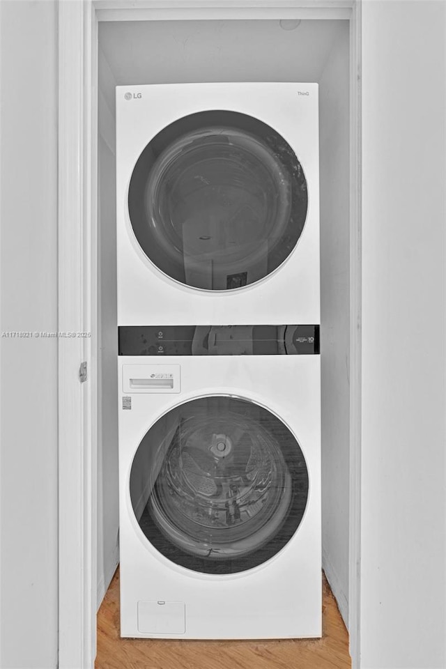 laundry area with wood-type flooring and stacked washing maching and dryer