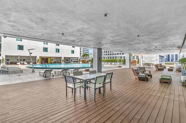 wooden terrace with outdoor lounge area, a patio area, and a community pool