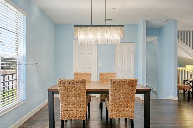 dining room with dark wood-type flooring and an inviting chandelier