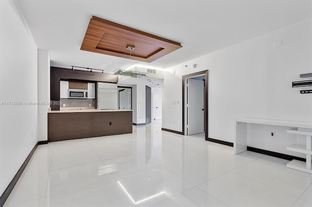 unfurnished living room with light tile patterned floors and a tray ceiling