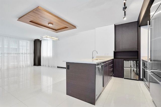 kitchen with kitchen peninsula, light tile patterned floors, sink, and appliances with stainless steel finishes