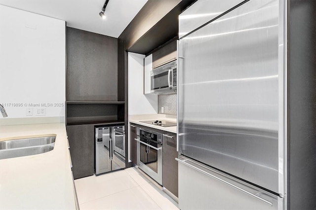 kitchen with rail lighting, sink, decorative backsplash, light tile patterned flooring, and stainless steel appliances