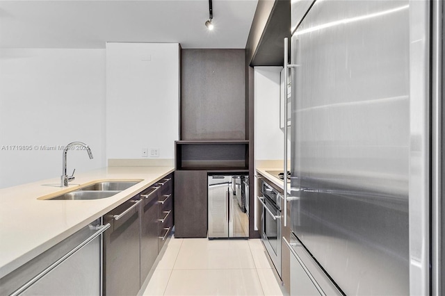 kitchen featuring rail lighting, sink, light tile patterned floors, and stainless steel appliances