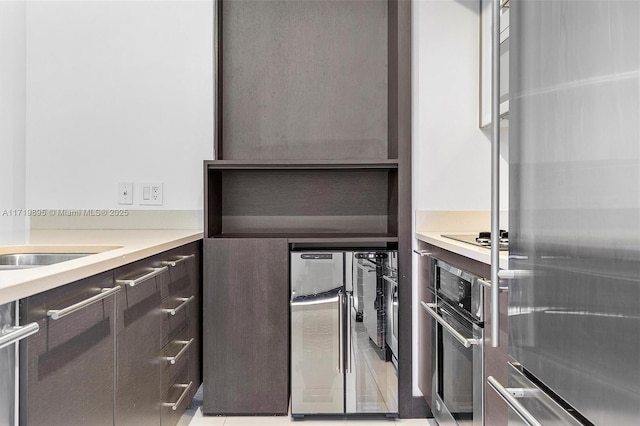 kitchen featuring beverage cooler, dark brown cabinetry, and appliances with stainless steel finishes