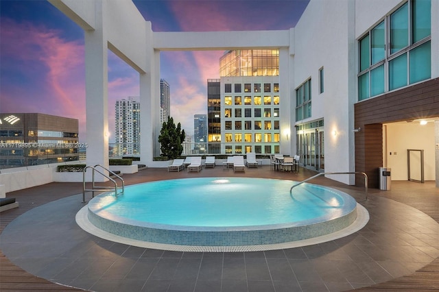 pool at dusk featuring a patio