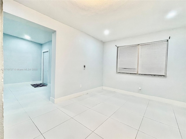 spare room with light tile patterned flooring and a textured ceiling