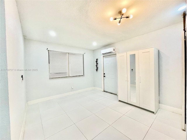 interior space featuring light tile patterned floors, a textured ceiling, and a wall unit AC