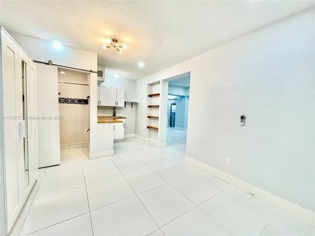 kitchen featuring white cabinets, butcher block countertops, light tile patterned floors, and a textured ceiling