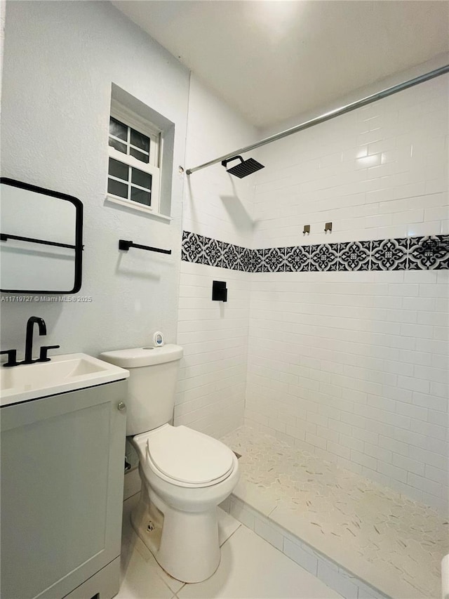 bathroom with a tile shower, tile patterned flooring, vanity, and toilet