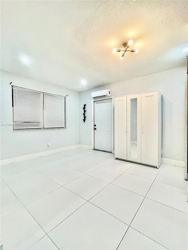 tiled spare room with a wall mounted air conditioner and a textured ceiling