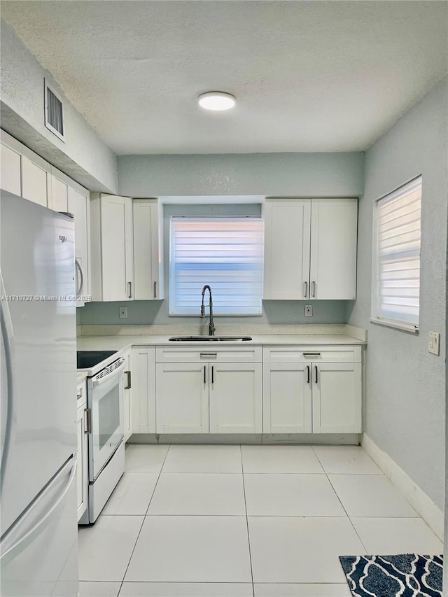 kitchen featuring white cabinetry, sink, light tile patterned floors, and white appliances