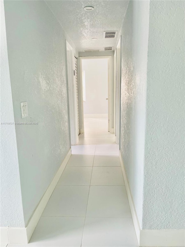 hallway with light tile patterned floors and a textured ceiling