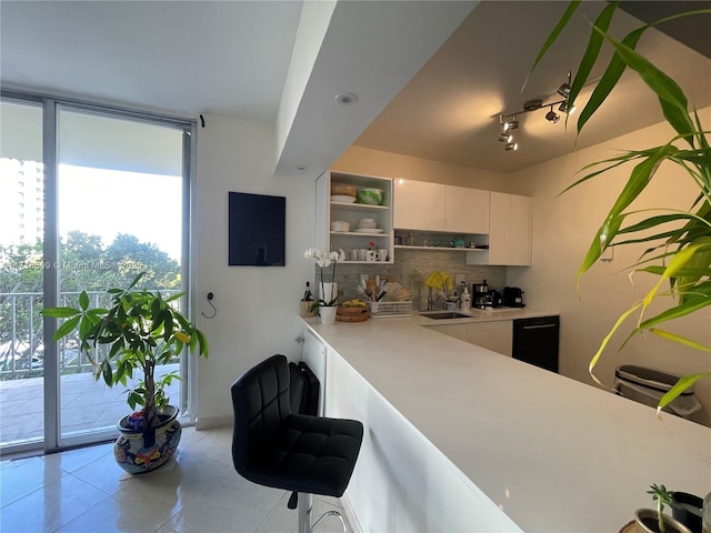 kitchen with white cabinets, backsplash, light tile patterned flooring, and sink