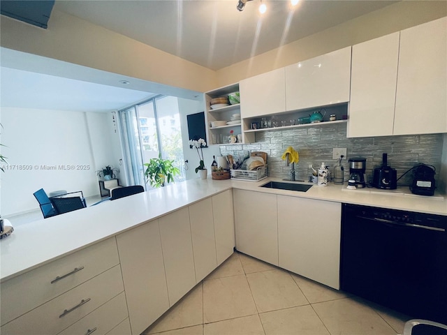 kitchen featuring backsplash, sink, light tile patterned floors, black dishwasher, and white cabinetry