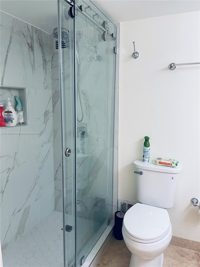 bathroom with tile patterned floors, a shower with shower door, and toilet