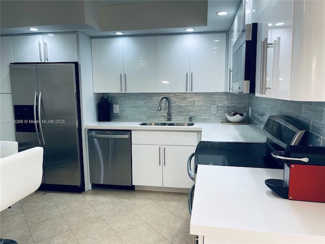 kitchen featuring white cabinetry, sink, backsplash, light tile patterned flooring, and appliances with stainless steel finishes