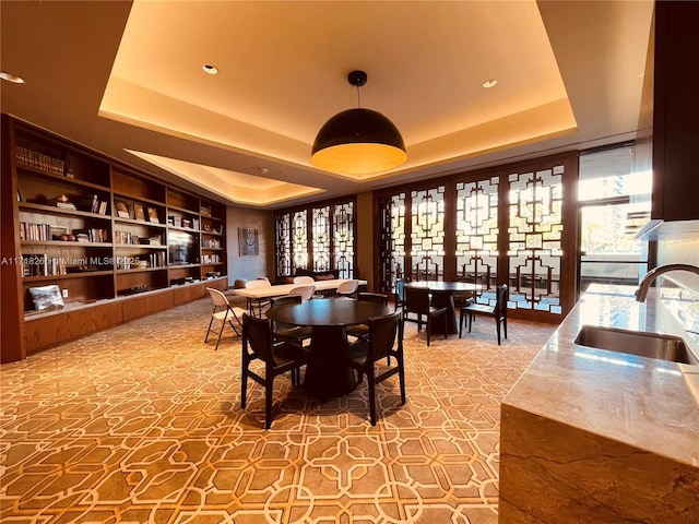 dining room with a tray ceiling, sink, and built in features