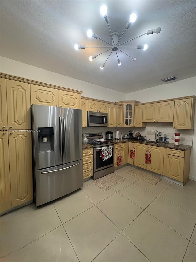 kitchen featuring light brown cabinets, an inviting chandelier, sink, light tile patterned floors, and appliances with stainless steel finishes