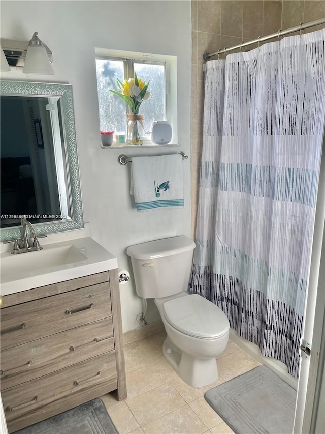 bathroom with toilet, tile patterned flooring, vanity, and walk in shower