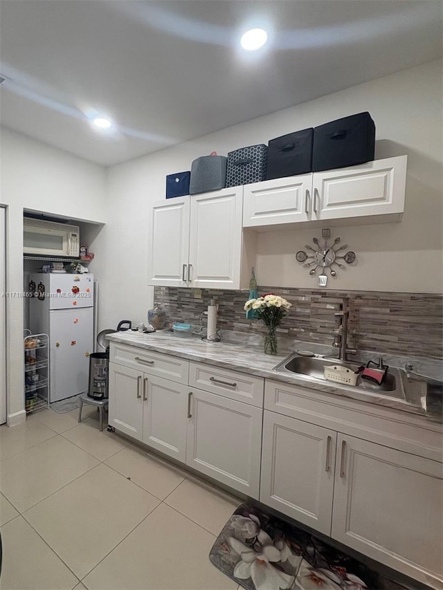 kitchen featuring decorative backsplash, white appliances, sink, white cabinets, and light tile patterned flooring