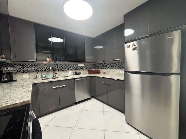 kitchen featuring light stone countertops, tasteful backsplash, stainless steel appliances, sink, and light tile patterned flooring