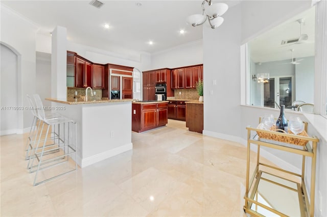 kitchen with tasteful backsplash, sink, kitchen peninsula, ornamental molding, and a breakfast bar area