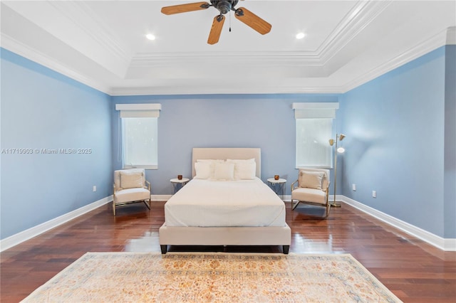 bedroom with ceiling fan, crown molding, dark wood-type flooring, and a tray ceiling