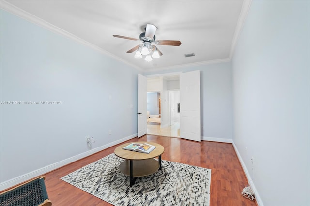 living area with crown molding, wood-type flooring, and ceiling fan