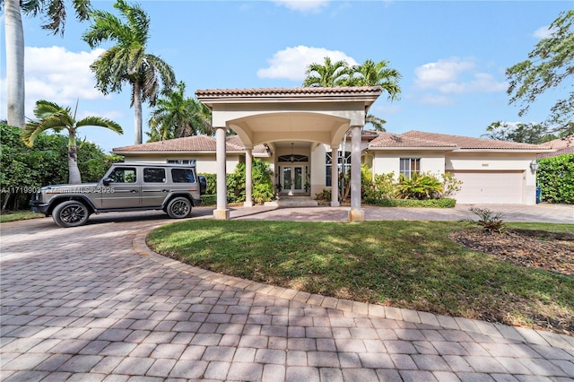 mediterranean / spanish home featuring a garage and a front lawn