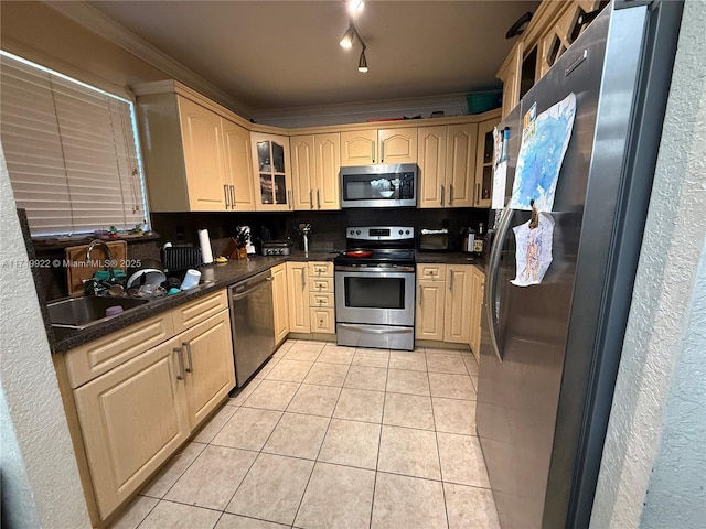 kitchen featuring tasteful backsplash, ornamental molding, stainless steel appliances, sink, and light tile patterned floors