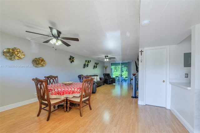 dining space with electric panel, ceiling fan, a textured ceiling, and light wood-type flooring