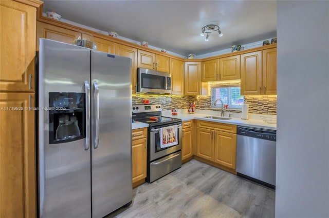 kitchen with light brown cabinetry, tasteful backsplash, stainless steel appliances, sink, and light hardwood / wood-style flooring