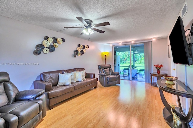 living room with ceiling fan, expansive windows, a textured ceiling, and hardwood / wood-style flooring