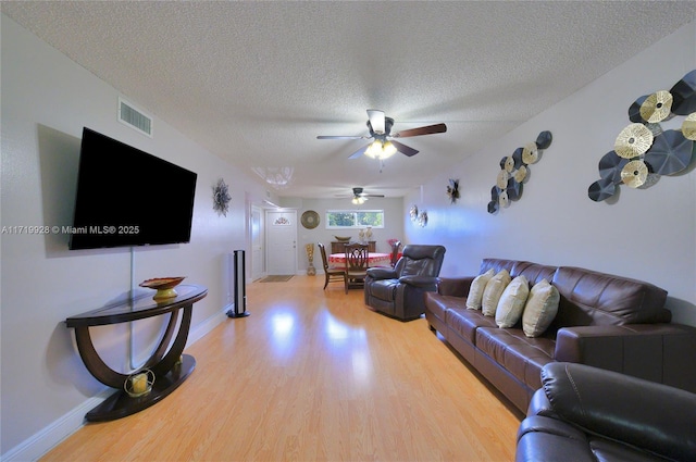 living room with ceiling fan, a textured ceiling, and hardwood / wood-style flooring