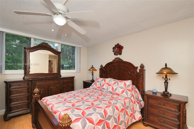 bedroom with ceiling fan, light hardwood / wood-style floors, and a textured ceiling