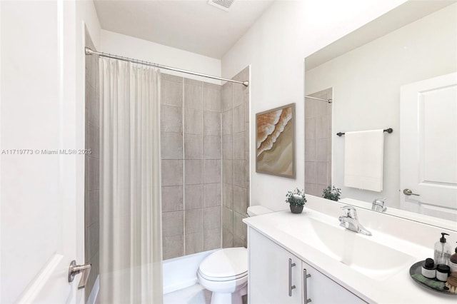 bathroom with a tile shower, vanity, and toilet