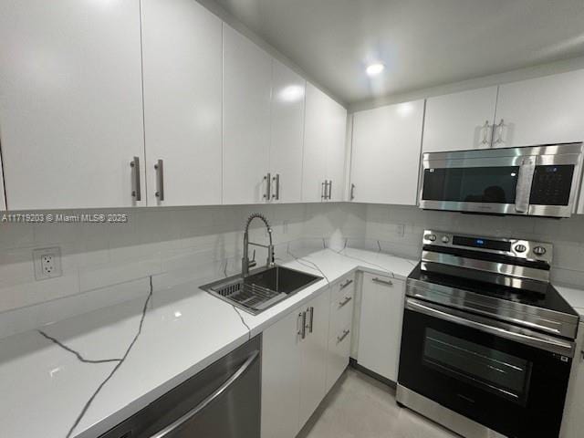 kitchen featuring backsplash, sink, white cabinetry, and stainless steel appliances