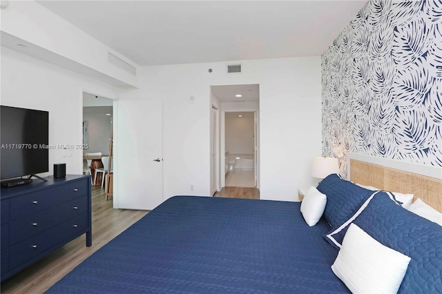 bedroom with wood-type flooring and ensuite bathroom