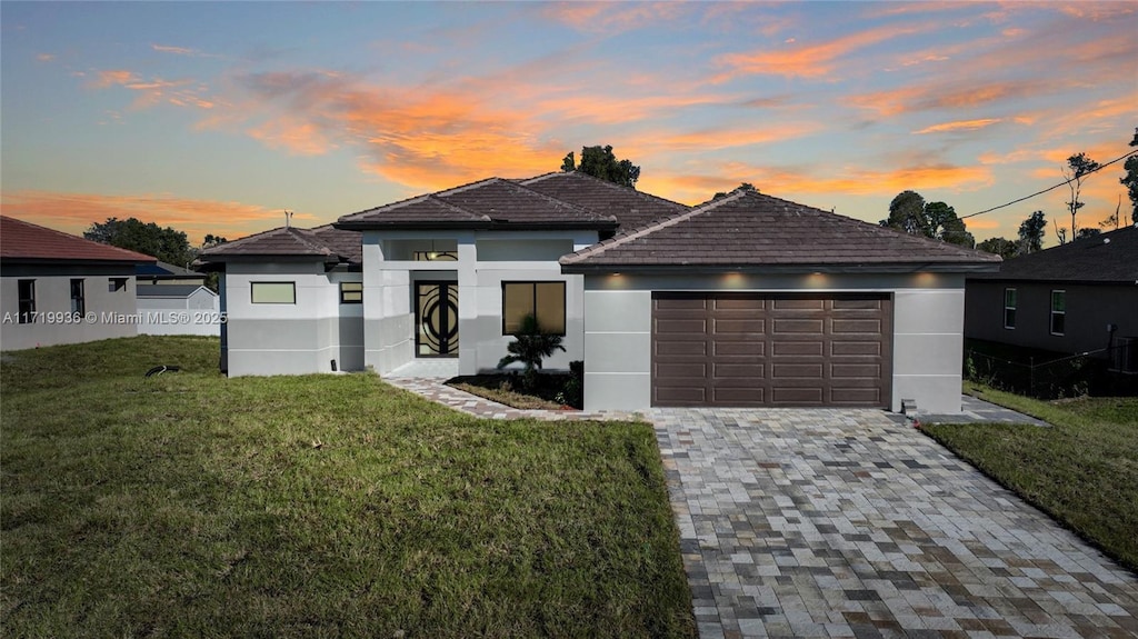 prairie-style house featuring a garage and a lawn