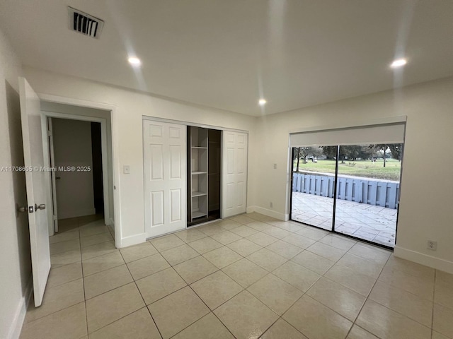 unfurnished bedroom with access to exterior, a closet, and light tile patterned flooring