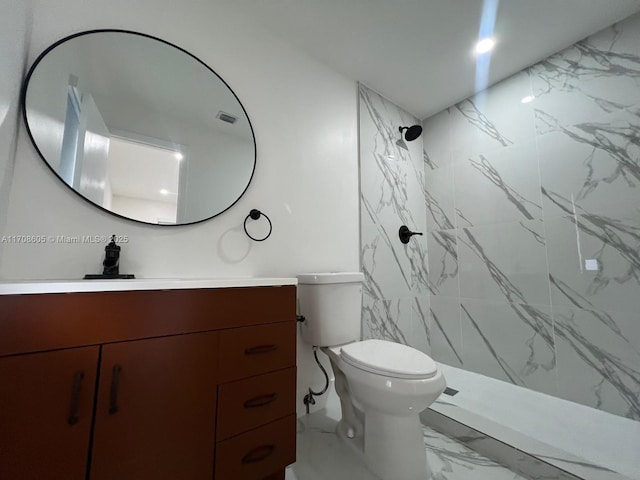 bathroom with a tile shower, vanity, and toilet