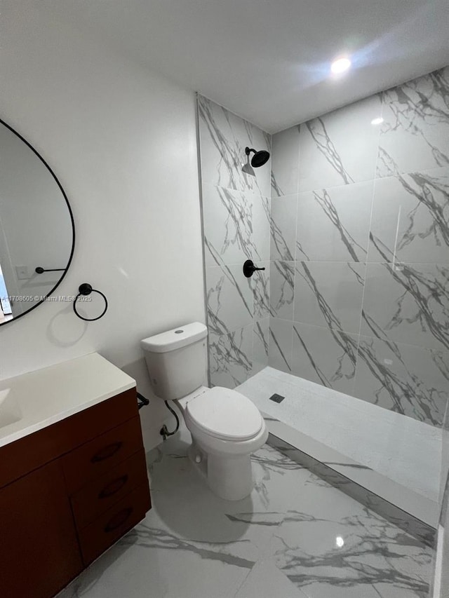 bathroom featuring toilet, vanity, and tiled shower