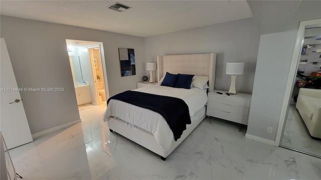 bedroom with a textured ceiling and ensuite bath