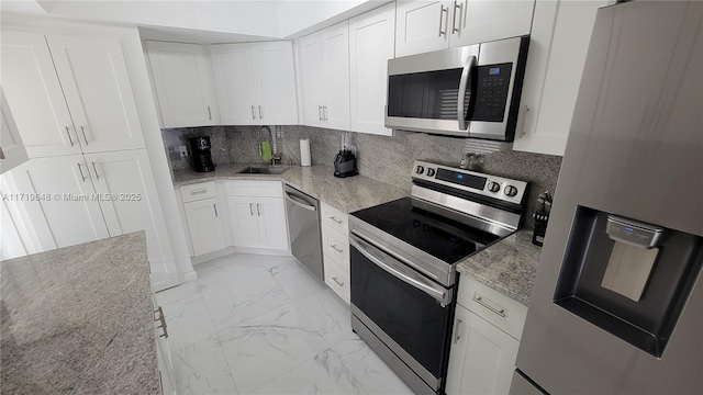 kitchen featuring appliances with stainless steel finishes, backsplash, light stone counters, sink, and white cabinetry